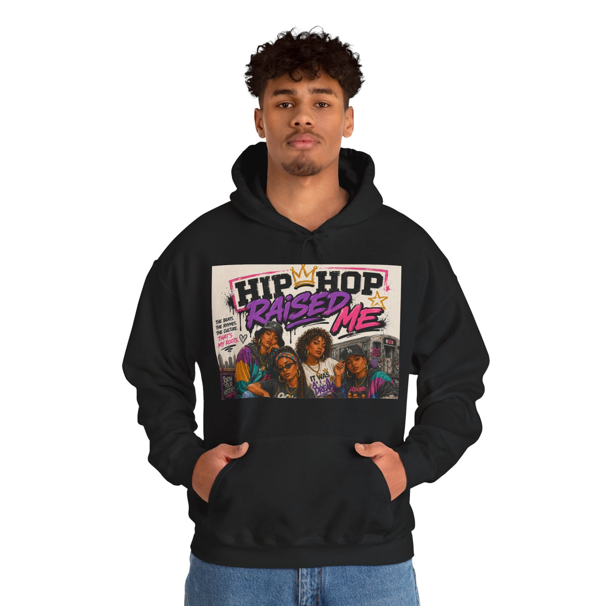 A man wearing a black pullover hoodie with a colorful graphic print on the front that reads 'HID HOP RAISED ME' with illustrated faces and graffiti-style lettering, paired with blue jeans against a plain white background.