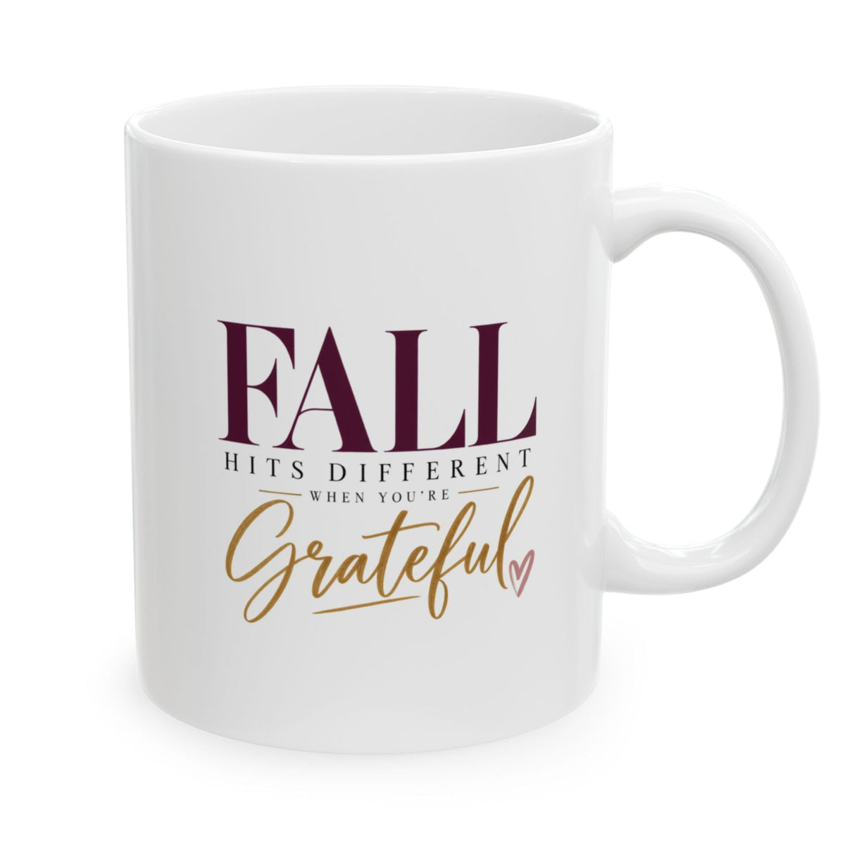 A white ceramic coffee mug with a handle, featuring the printed text 'FALL HITS DIFFERENT WHEN YOU'RE Grateful' in dark burgundy and gold lettering, on a plain white background.