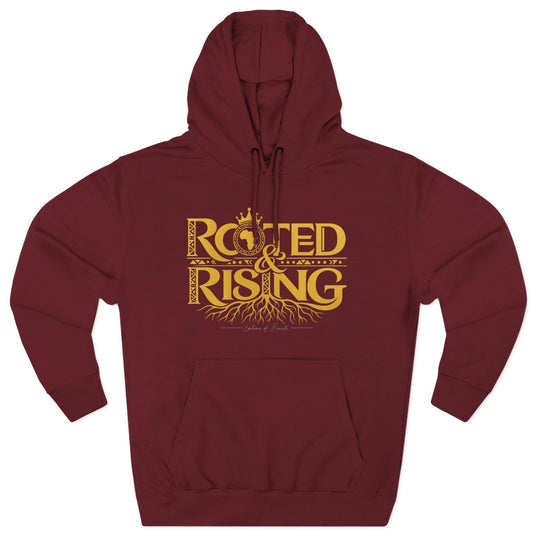 A maroon pullover hoodie with a gold graphic print on the chest reading 'ROOTED & RISING' with decorative roots and a crown, shown on a plain white background.