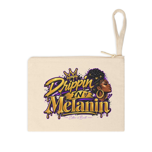 A cream canvas zip pouch with a matching fabric loop handle, featuring a colorful graphic print on the front that reads 'Drippin' IN 'Melanin' with a crown and profile illustration of a woman.