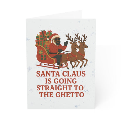 A white greeting card with a humorous Christmas illustration showing Santa Claus in his sleigh being pulled by two reindeer, with the text 'SANTA CLAUIS GOING STRAIGHT TO THE GHETTO' printed in red.