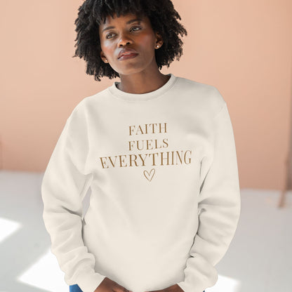 Person wearing a cream sweatshirt with 'Faith Fuels Everything' text in colorful gold letters against a light background.