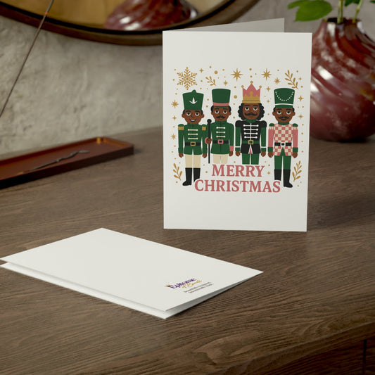 A white Christmas greeting card standing on a wooden table, printed with four nutcracker figures and the words “MERRY CHRISTMAS.” A matching white envelope lies in front.