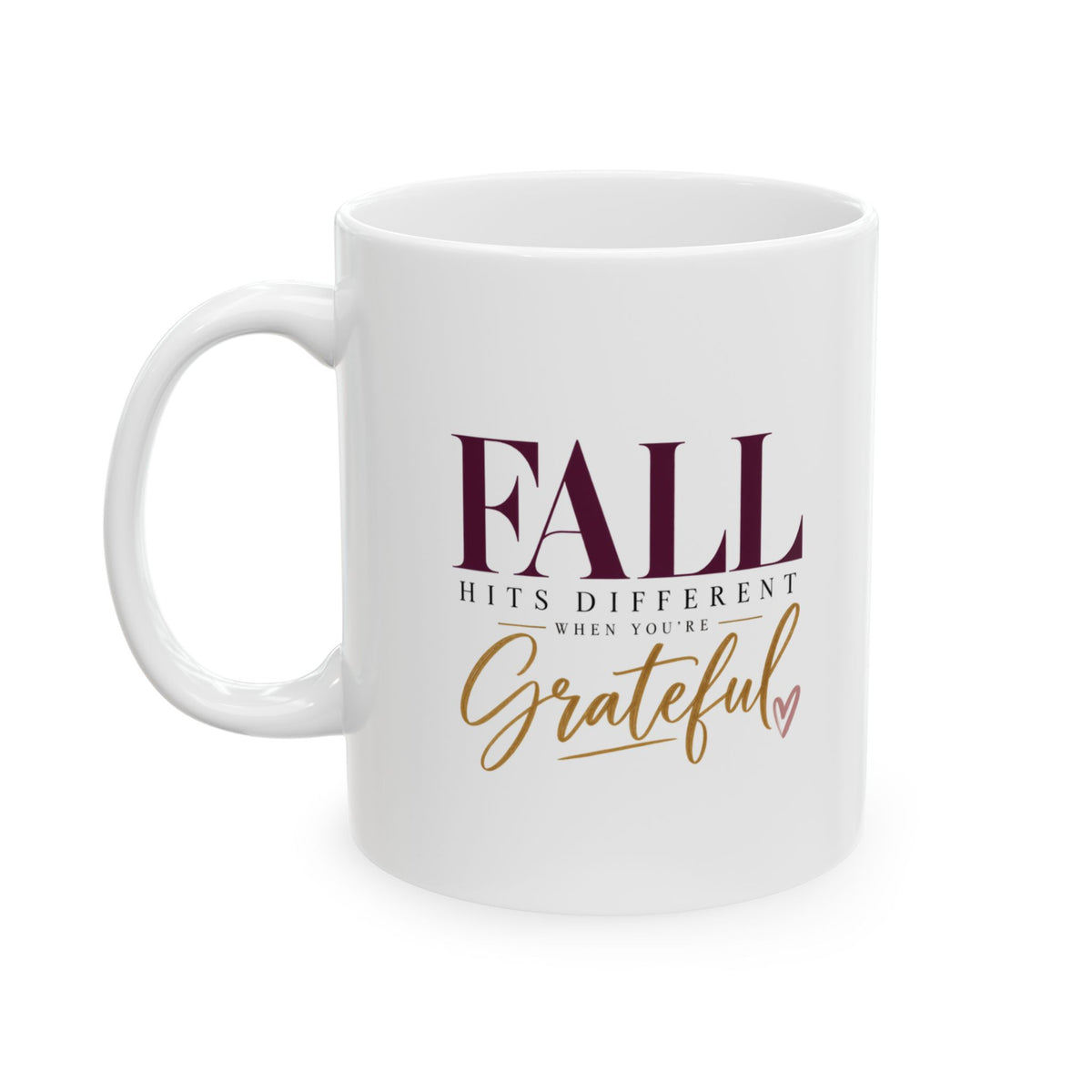 A white ceramic coffee mug with a handle on the left, featuring the printed text 'FALL HITS DIFFERENT WHEN YOU'RE Grateful' in dark burgundy and gold lettering, set against a plain white background.