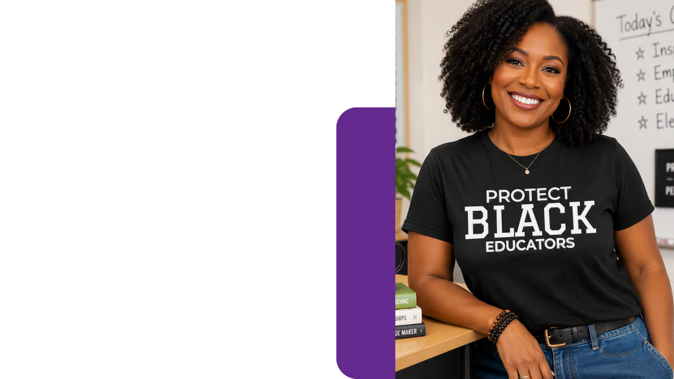 A smiling woman with curly hair stands indoors wearing a black graphic T-shirt that reads 'PROTECT BLACK EDUCATORS' in white text, paired with blue jeans. The background includes a whiteboard and desk.